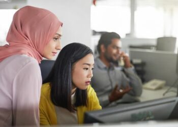 Deux femmes au travail, dont l'une porte un voile.